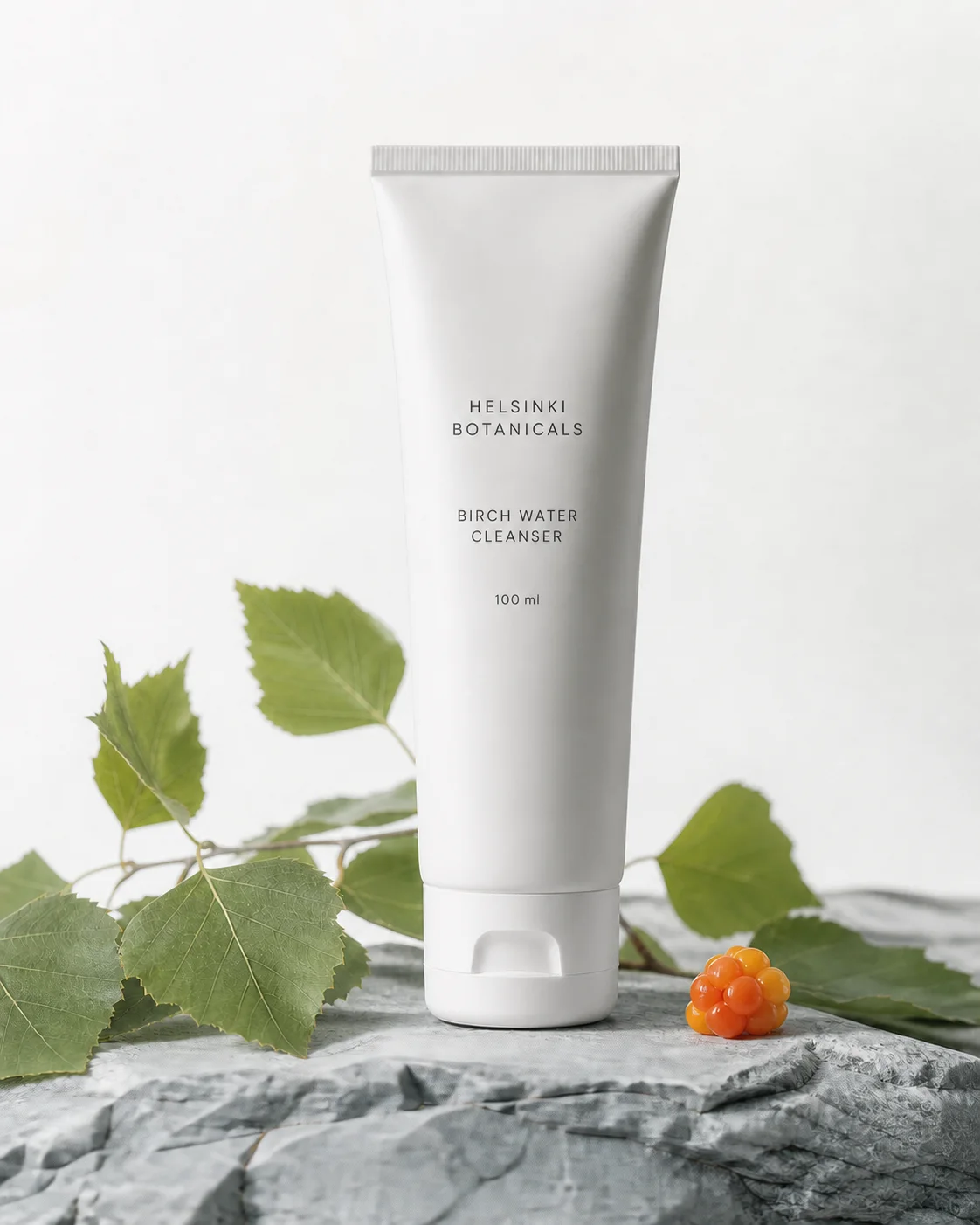 White Birch Water Cleanser tube beside birch leaves and cloudberries on pale stone